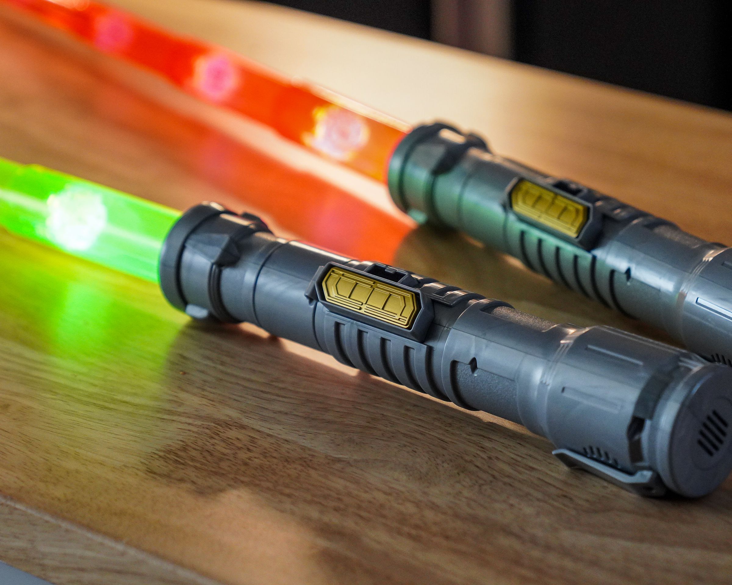 Lightsaber toys in silver, with golden sliding switches on the side, identical save for their red and green blades.