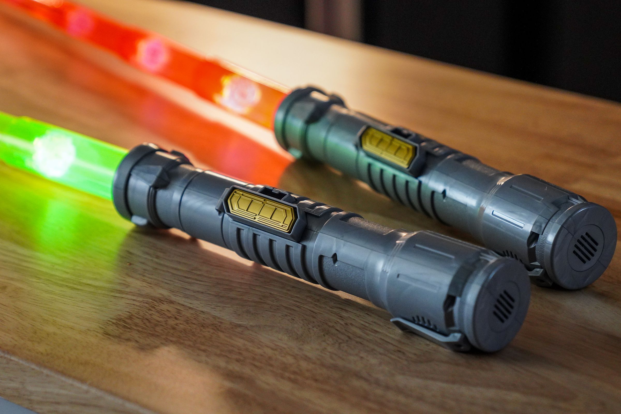 Lightsaber toys in silver, with golden sliding switches on the side, identical save for their red and green blades.